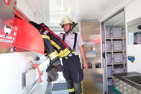 Hygiene-Abrollcontainer der Feuerwehren Bad Schwalbach: Philipp Weitz demonstriert, wie beim Einsatz verschmutzte Kleidung deponiert wird.
