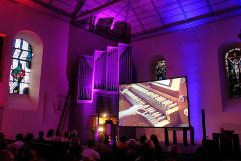 Bei der Orgel-Show in der Reformationskirche wird der Altarraum von einem großen Bildschirm dominiert, Laserpunkte verleihen der Decke die Anmutung eines Sternenhimmels. Martin Fromme