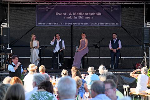 Keith Ikaia-Purdy (links) prostet dem Publikum zu, während auf der Bühne (v.l.) Katharina Reimann, Pascal Mehl sowie Elizabeth und Alex Winn zuhören. Foto: DigiAtel/Heibel