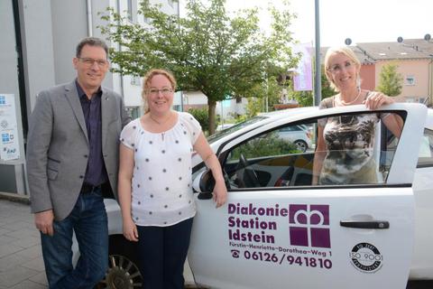 Pfarrer Markus Eisele, die neue Geschäftsführerin der Diakoniestation Idstein, Stefanie Dittrich, und ihre Vorgängerin Julia Ludwig-Hartmann (von links) vor einem der 20 Autos, die der Einrichtung zur Verfügung stehen.Foto: wita/Martin Fromme  Foto: wita/Martin Fromme