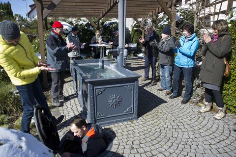 Der Vize-Brunnenmeister Andreas Schlögl (unten links) schließt unter dem Beifall der Besucher das Wasser für den Brunnen an. Foto: Mallmann/AMP