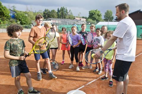 Der Tennistrainer Kevin Glapa (rechts) erklärt den Schülern beim Tenniscamp in Steinfischbach die Grundlagen der Sportart. Es sind Kinder im Alter von  vier bis elf  Jahren dabei. Am letzten Tag des Camps können sie das Sportzeichen des Hessischen Tennis-Verbandes erlangen. Mallmann/AMP