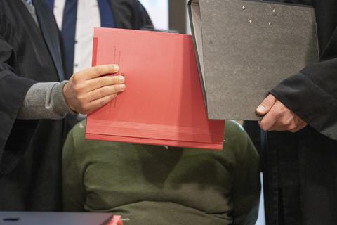 Mit Aktenmappen schirmen die Anwälte den Angeklagten Sven B. während des Prozesses im Landgericht in Frankfurt ab. 