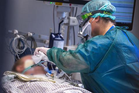 Eine Intensivschwester betreut einen Patienten mit Covid-19 in einem der Behandlungszimmer der Intensivstation. Foto: dpa