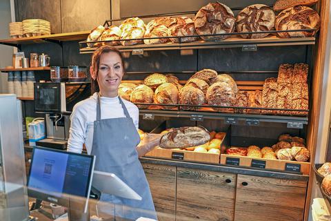 Die Bäckerei „Köstner” (hier Verkäuferin Zita Tamas mit frischem Brot in der Hand) trotzt der Mehrfachbelastung durch klare Kalkulation, Sortimentsreduzierung und Stammkundenbindung.