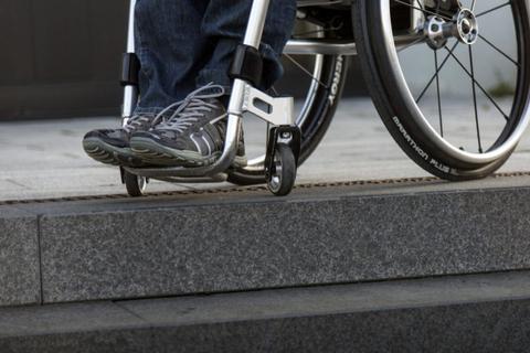 Ein Rollstuhlfahrer steht in seinem Rollstuhl an einer Treppe. Alltag für viele Betroffene.