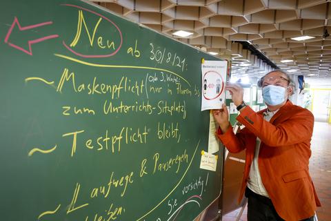 Niko Lamprecht, Schulleiter der Carl-von-Ossietzky-Schule, vor einer Tafel mit den aktuellen Corona-Regeln.           Foto: Sascha Kopp