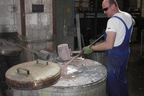 Der Mitarbeiter in der Aliminiumgießerei, Alexander Riebel, schöpft aus dem Schmelztiegel. Foto: Hendrik Jung  Foto: Hendrik Jung