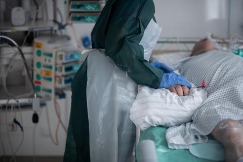 Eine Mitarbeiterin der Pflege in Schutzausrüstung betreut einen Covid-Patienten. Foto: dpa