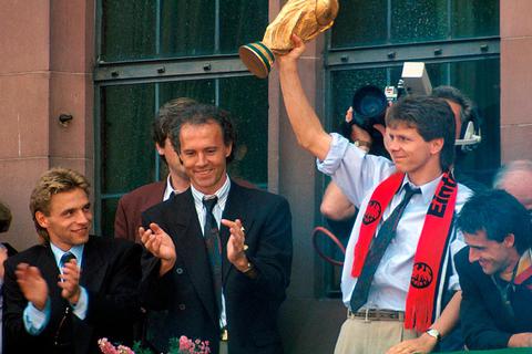 Mit dem WM-Pokal und Eintracht-Schal: Andreas Möller neben Teamchef Franz Beckenbauer beim Empfang der Nationalmannschaft  im Jahr 1990 auf dem Frankfurter Römer. Links Thomas Häßler, rechts Pierre Littbarski. Foto: imago 