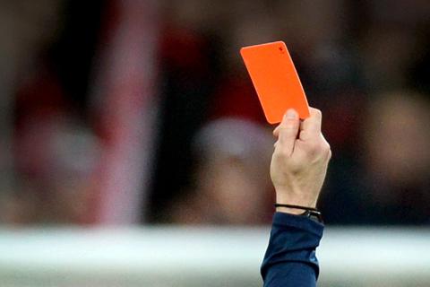 Ein Schiedsrichter zeigt einem Fußballspieler die rote Karte.