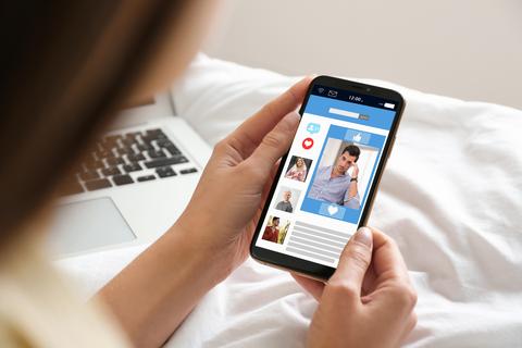 Eine junge Frau besucht eine Online-Dating-Site per Smartphone.