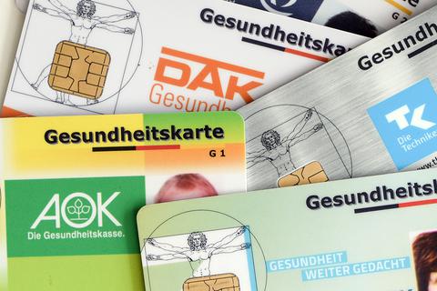 Gesundheitskarten verschiedener Krankenkassen liegen auf einem Tisch. Foto: Jens Kalaene/ZB/dpa 